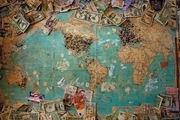 Carte du monde avec billets de banque. Copyright : Christine Roy sur Unsplash